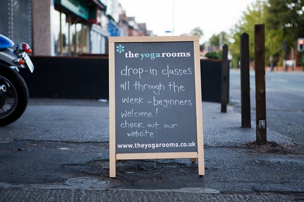 A handwritten notice board on Barlow Moor Road advertising yoga classes